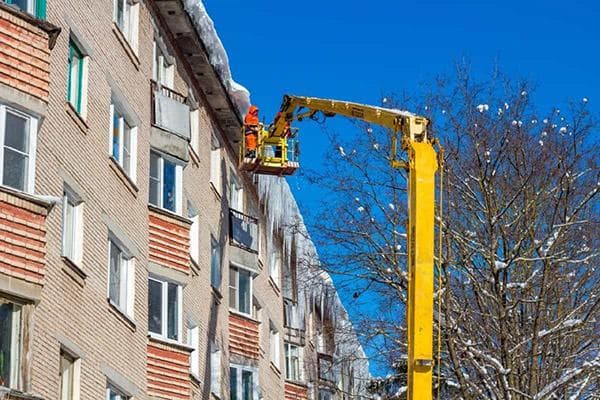 Dachreinigung von Schnee von einer selbstfahrenden Hebebühne