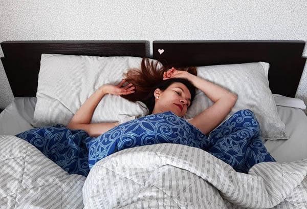 Frau im Bett mit bunter Bettwäsche
