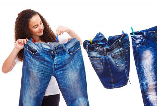 Eine junge Frau hängt Jeans zum Trocknen auf