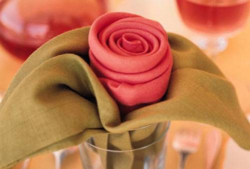 Im Glas zu einer Rose gefaltete Servietten