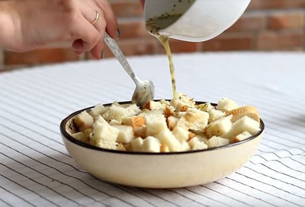 Das Brot für die Croutons wird mit dem gewürzten Öl beträufelt.