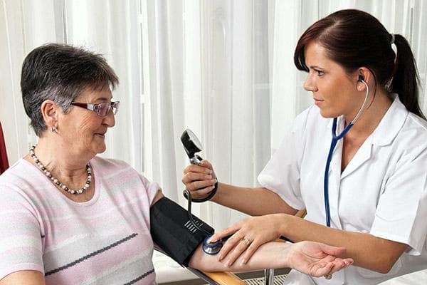 Der Arzt misst den Blutdruck einer älteren Patientin