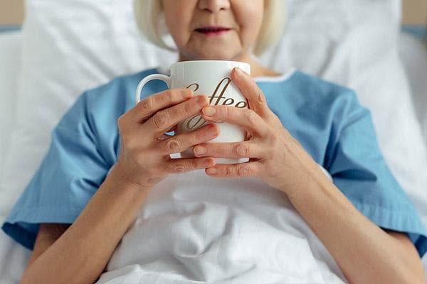 Ältere Frau trinkt Kaffee im Bett