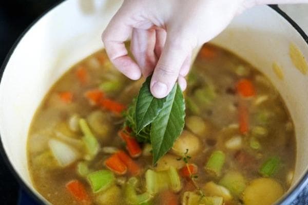 Hinzufügen von Lorbeerblättern in die Suppe