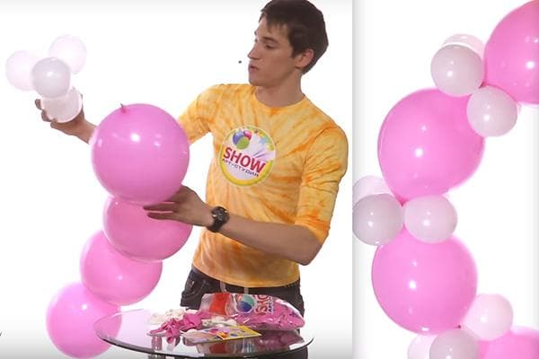 Ein Mann baut einen Bogen aus Luftballons