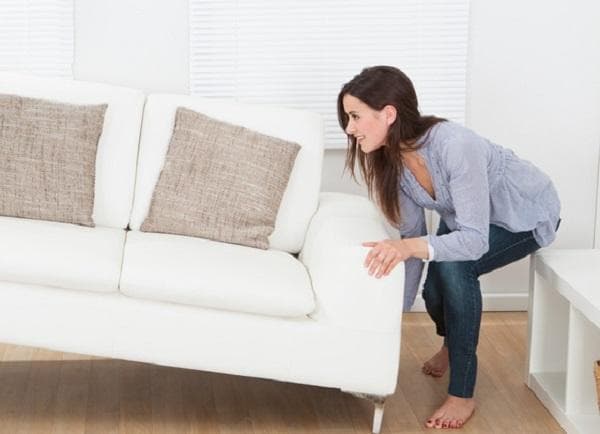 Eine junge Frau schiebt ein Sofa