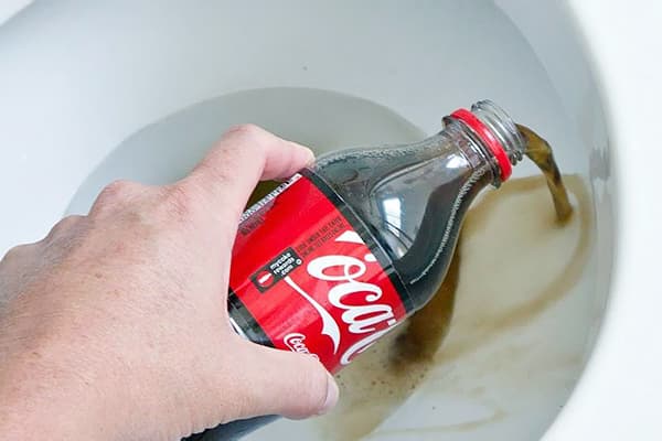 Ein Mann gießt Coca-Cola in die Toilette