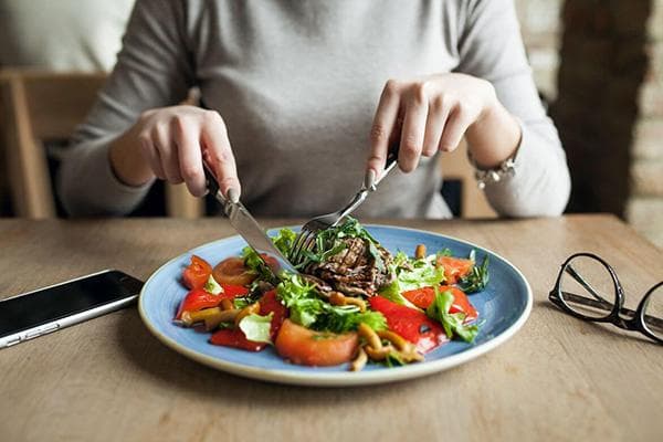 Eine Frau isst Fleisch und Salat