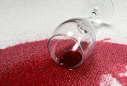 Verschütteter Wein auf einem hellen Teppich