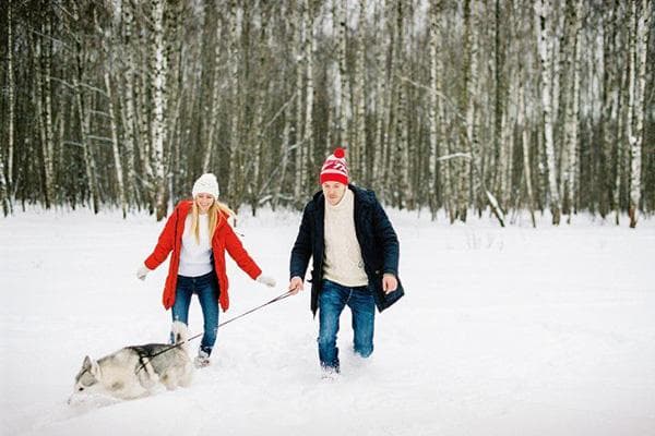 Paar geht im Winter mit dem Hund spazieren
