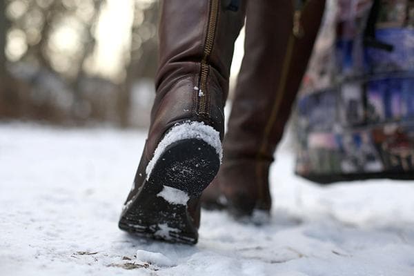 Eine Frau geht in Stiefeln durch den Schnee
