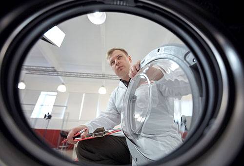 Mann studiert eine Waschmaschine