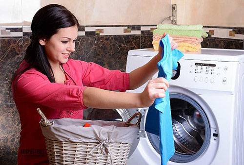 Eine Frau entnimmt Wäsche aus der Waschmaschine