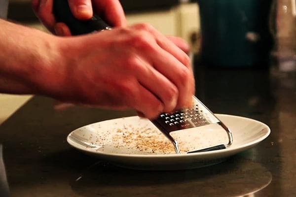 Ein Mann reibt Muskatnuss auf einer Reibe