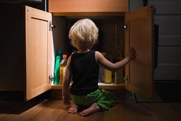 Kind am Schrank mit Haushaltschemikalien