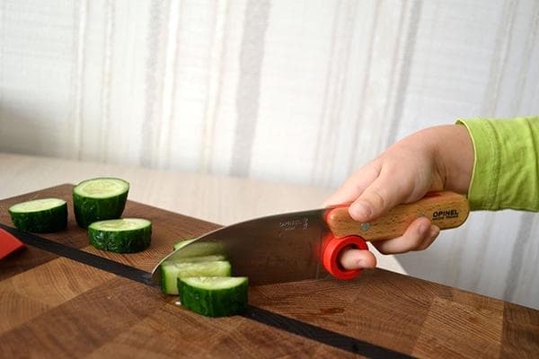 Ein Kind schneidet Gemüse mit einem Messer