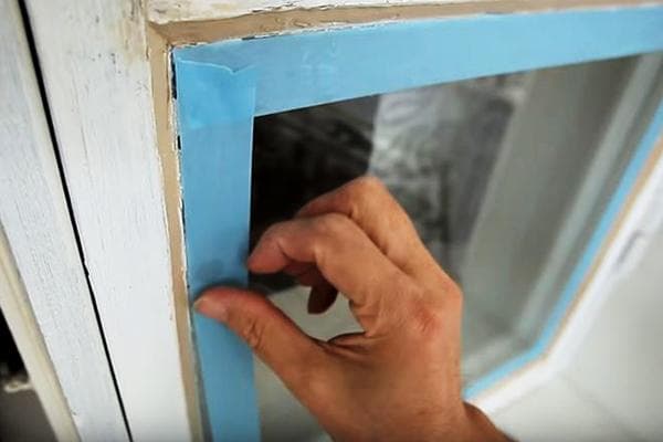 Anbringen von Malerkrepp zum Schutz der Fensterscheiben beim Streichen des Rahmens