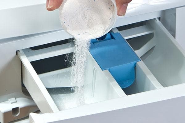 Einfüllen des Waschpulvers in das Einspülfach der Waschmaschine