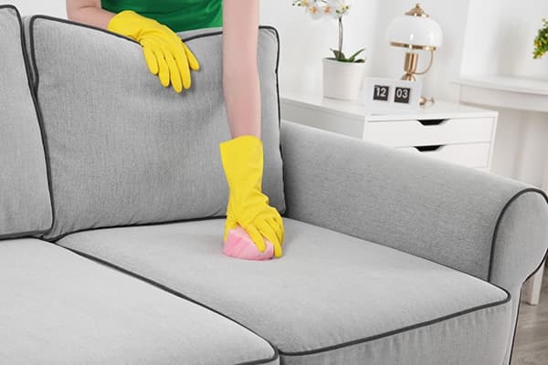Eine Frau reinigt ein Sofa