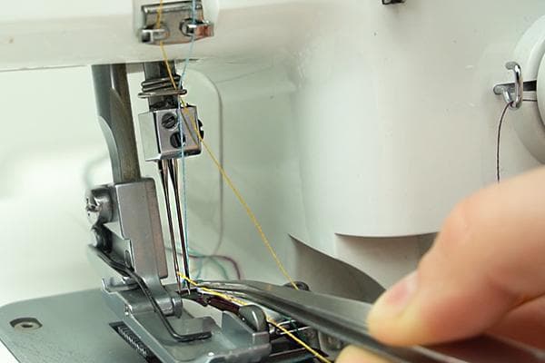 Einfädeln des Fadens in die Overlock-Nadel mit einer Pinzette
