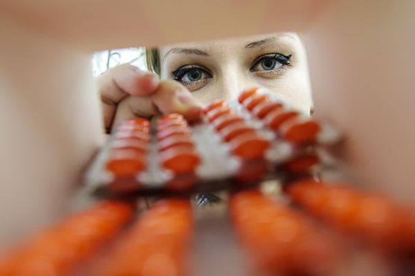 Eine junge Frau überprüft das Verfallsdatum von Tabletten