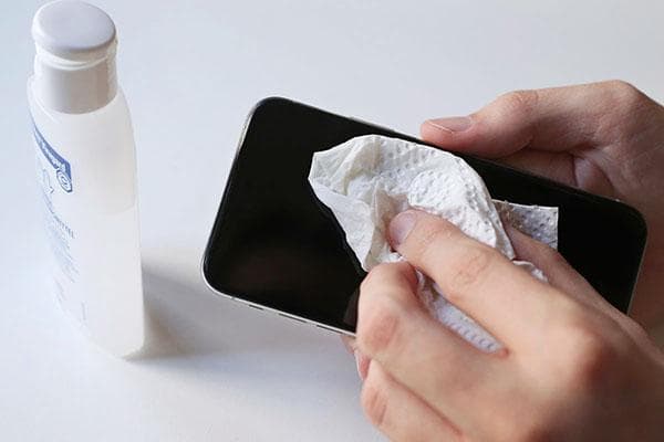 Behandlung des Smartphones mit einer Desinfektionslösung