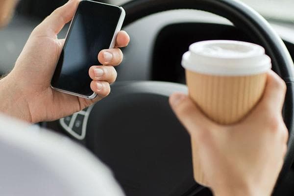 Ein Autofahrer trinkt Kaffee