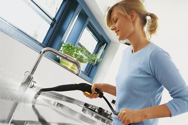 Eine Frau behandelt Küchenoberflächen mit einem Dampfreiniger