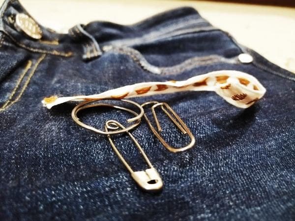 Jeans, Sicherheitsnadel und Ring an Jeans