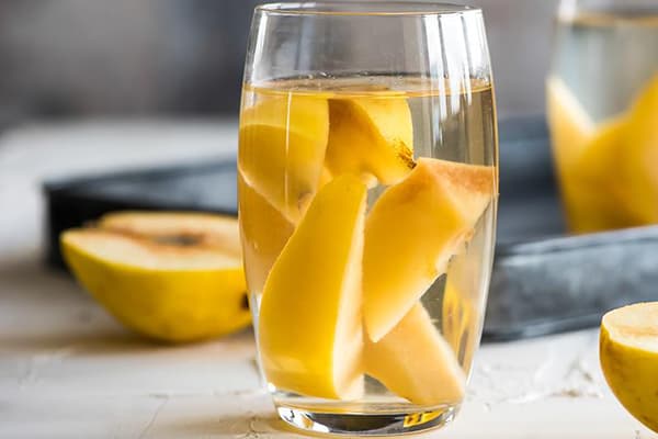 Quittenstücke in einem Glas Wasser