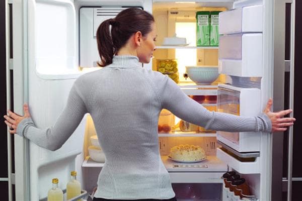 Frau vor einem offenen Kühlschrank