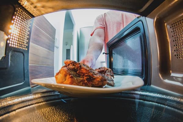 Ein Mann stellt Fleisch in die Mikrowelle