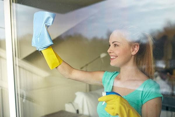 Eine Frau behandelt eine Fensterscheibe gegen Beschlagen