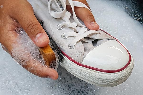 Waschen weißer Sneaker in Seifenwasser