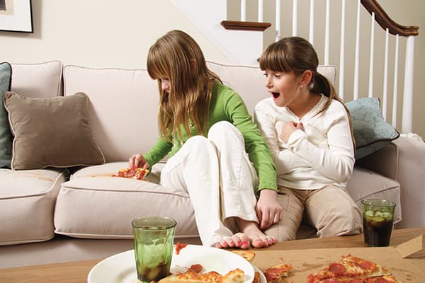 Ein Mädchen hat ein Stück Pizza auf das Sofa fallen lassen