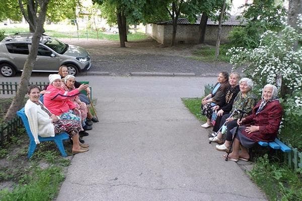 Rentnerinnen auf Bänken am Hauseingang
