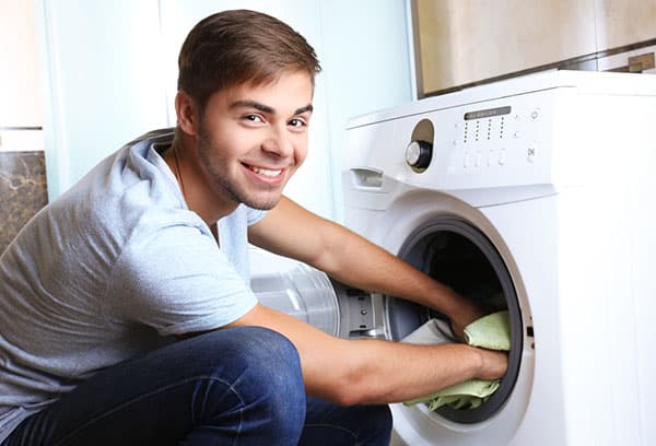 Ein Mann entnimmt Wäsche aus der Waschmaschine