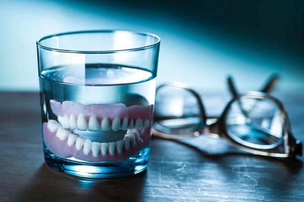 Zahnprothese in einem Glas Wasser