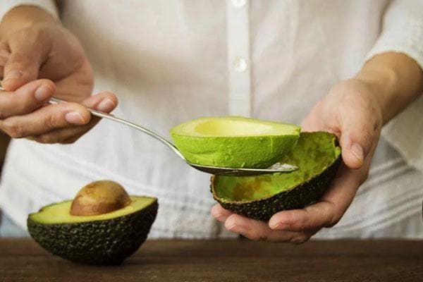 Avocadofruchtfleisch mit einem Löffel entnehmen
