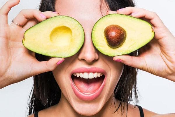 Junge Frau mit aufgeschnittener Avocado