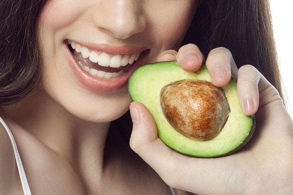 Frau mit einer halben Avocado