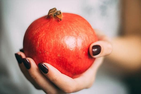 Frau hält einen Granatapfel in der Hand