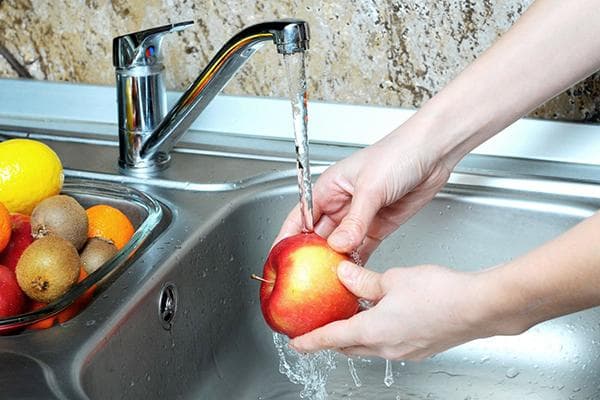 Waschen eines Apfels unter fließendem Wasser
