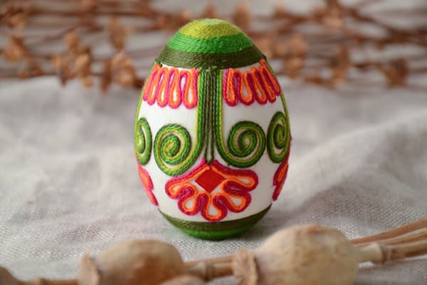 Osterei, verziert mit bunten Fäden