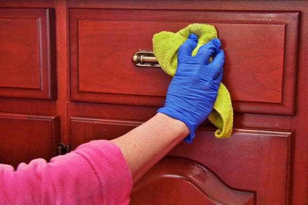 Eine Frau wischt Möbel mit einem feuchten Tuch ab