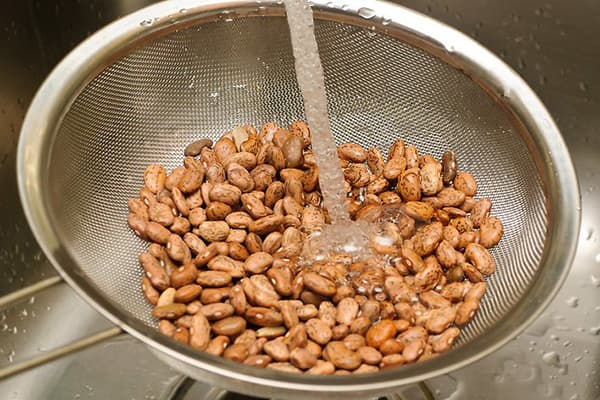 Abwaschen der Bohnen unter fließendem Wasser