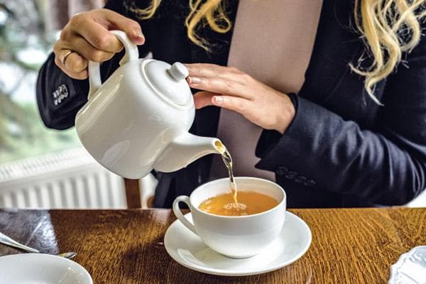 Eine Frau gießt Tee in eine Tasse