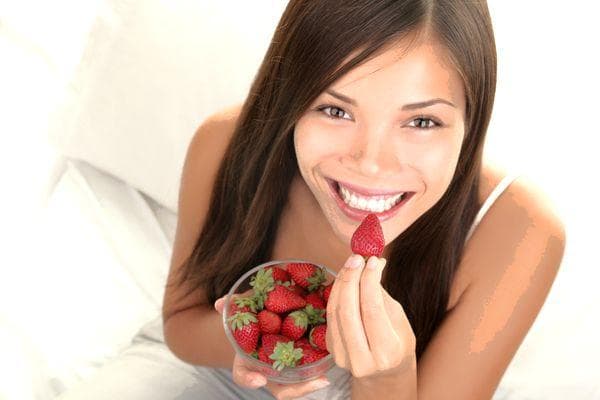 Eine junge Frau isst Erdbeeren