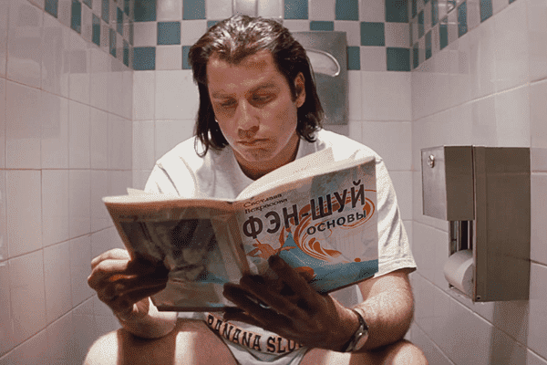 John Travolta liest ein Buch über Feng Shui.