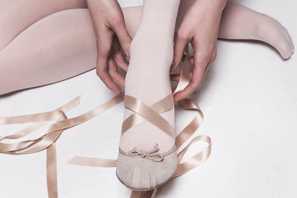 Eine Frau zieht Tanzballettschuhe an.